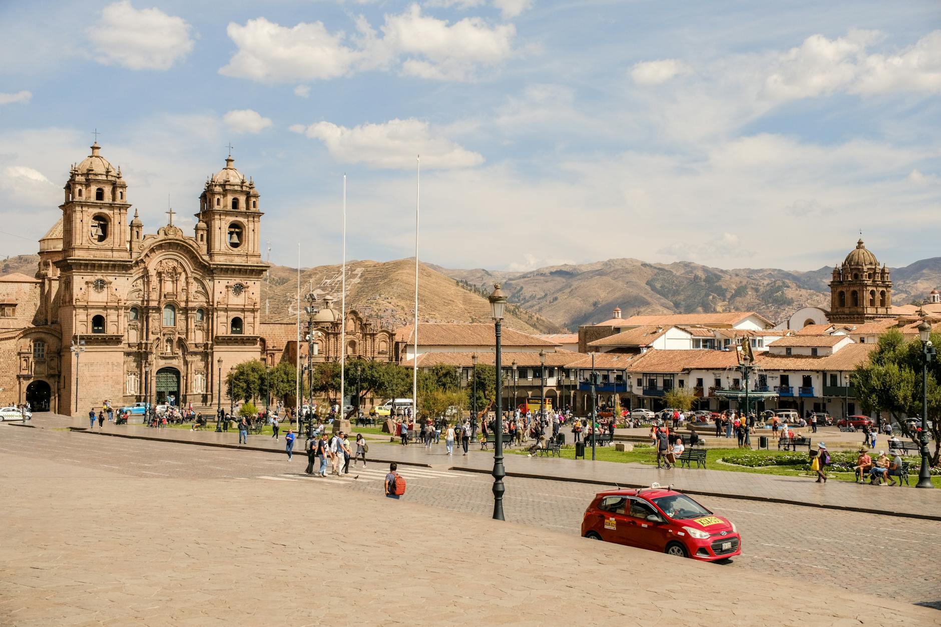 A vibrant view of a historic square in Cusco, Peru, featuring a cathedral, people, and street life.